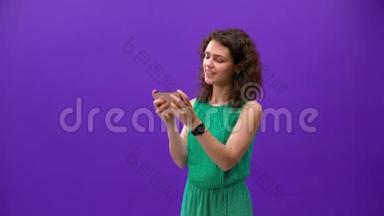 Curly女孩用一个紫色背景的<strong>新手机</strong>玩游戏